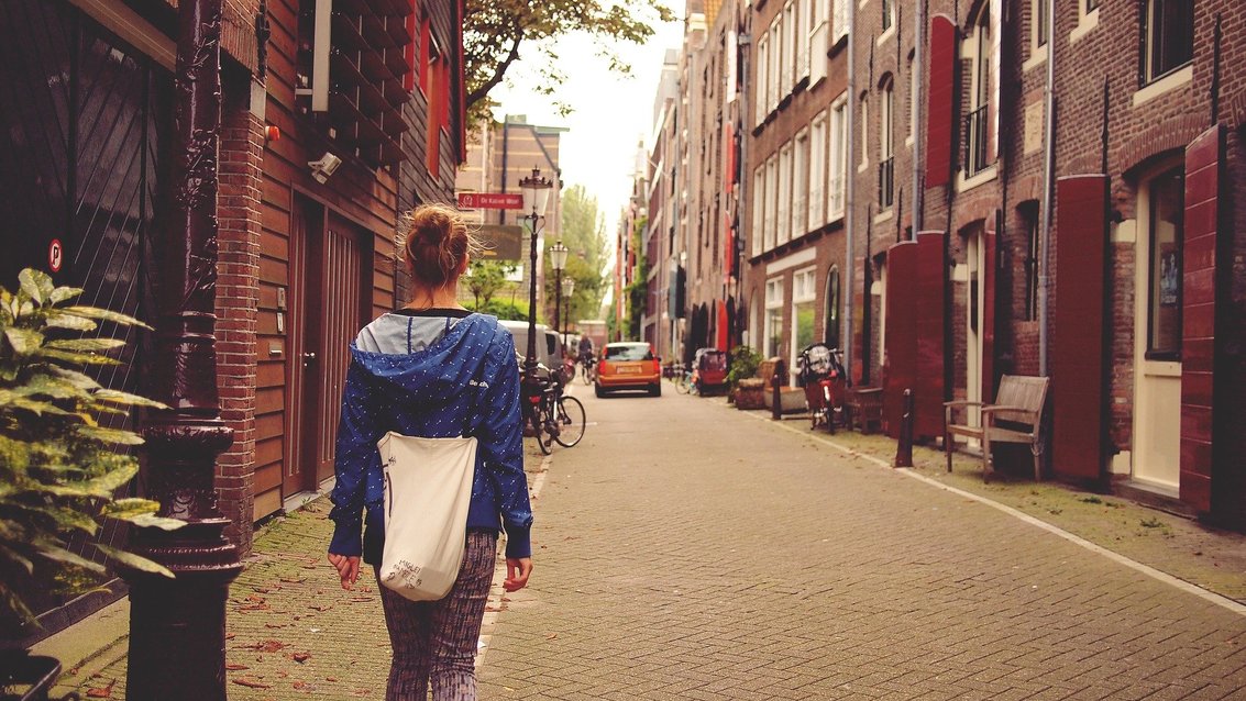 Junge Frau geht in einer Gasse in Amsterdam