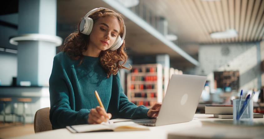 Junge Frau mit Kopfhörern in einer Bibliothek