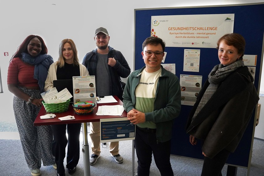 Eine Gruppe Studierender vor einer Plakatwand mit Projektinfos