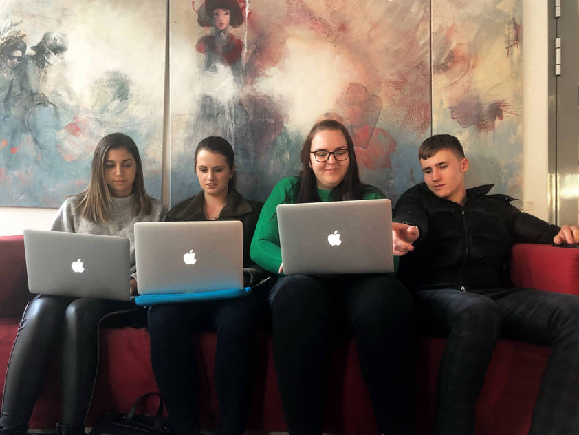 Student Katharina Landl sits with her fellow students on a red sofa at Campus Eisenstadt